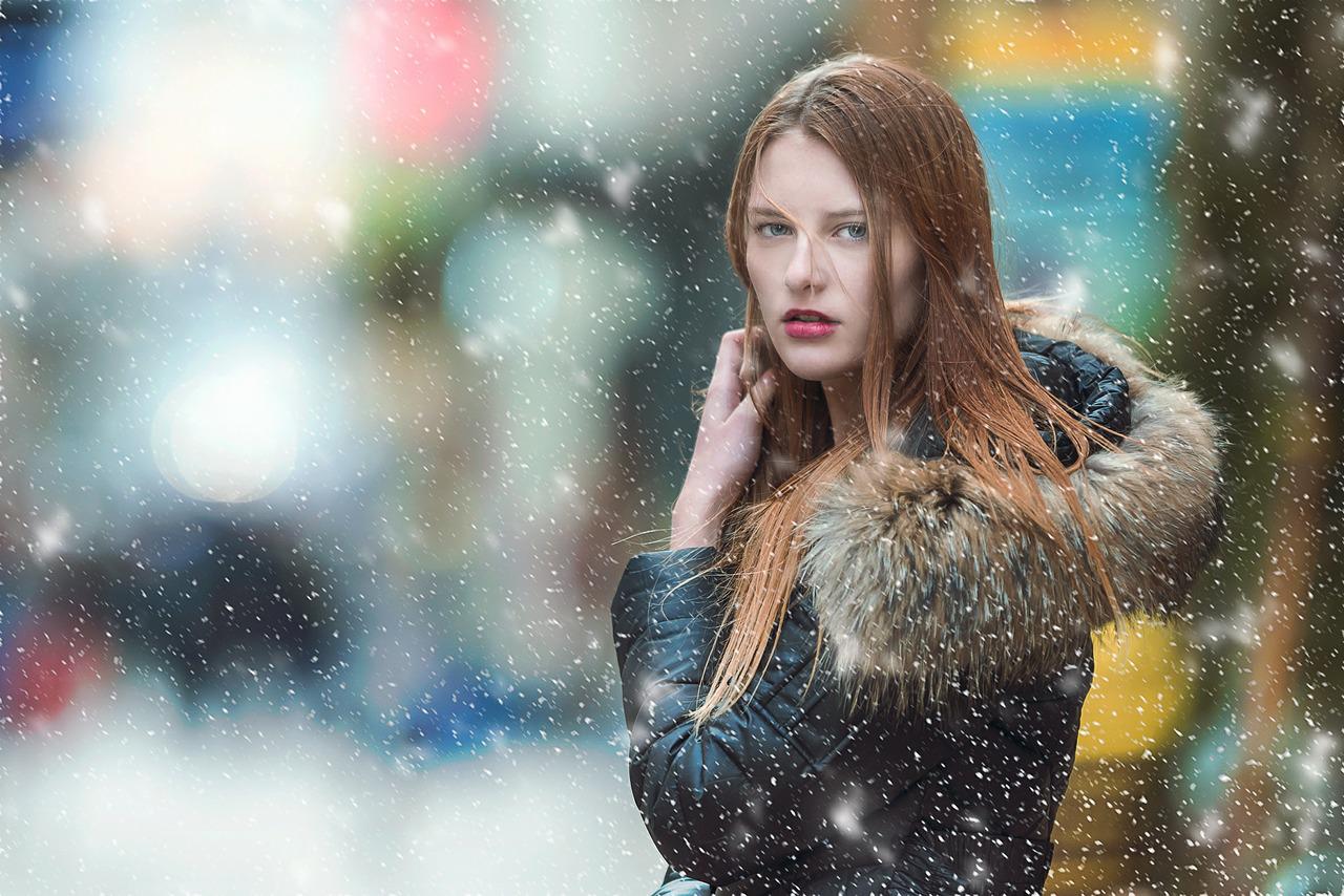 雪の中カメラを見つめる赤毛の女性