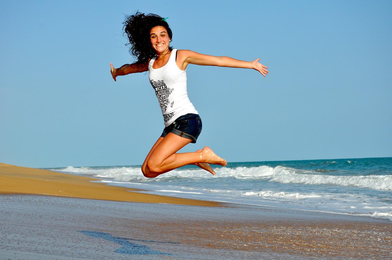 海辺で飛び跳ねる女性